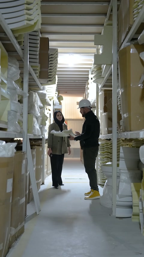 Worker in cap shows an ornamental element to the person across from him