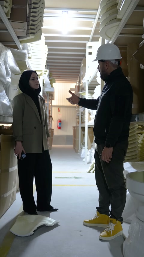 Worker in cap explains product features with hand gestures in the production area