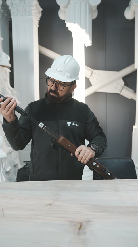 Atölyedeki uygulayıcı tüfeği kaldırarak namlu bölümünü dikkatle inceliyor.