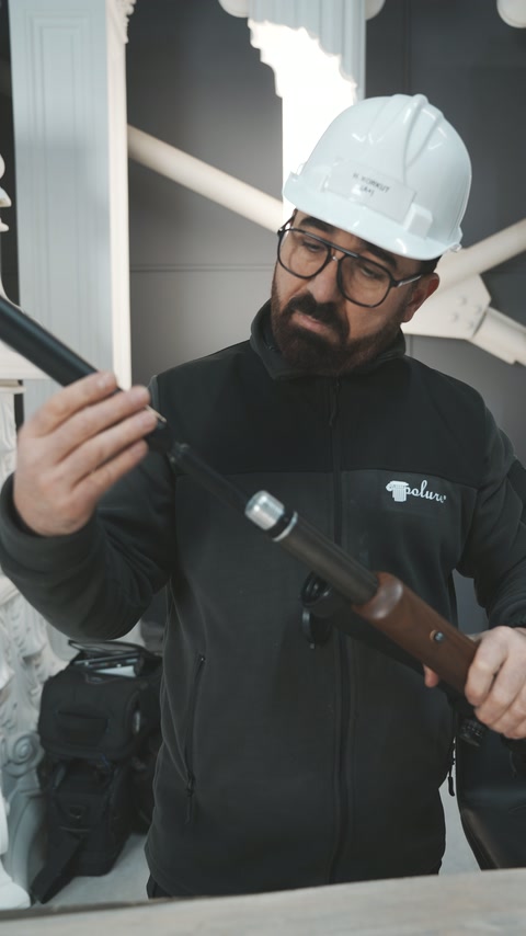 Dekoratif sütunların önündeki uygulayıcı namlu ucunu incelemeyi sürdürüyor.