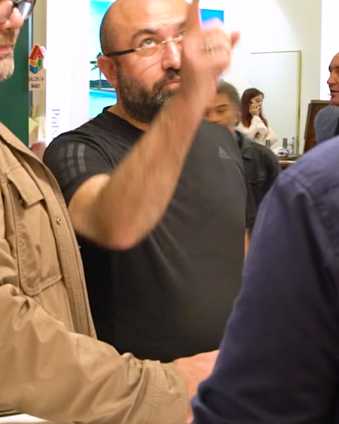 Uomo gesticola mentre parla all'ingresso dello stand espositivo