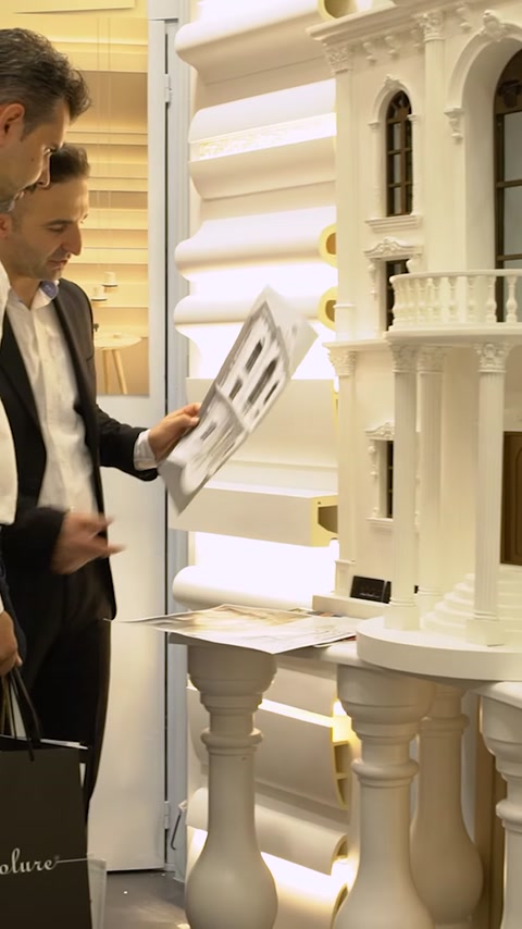 Uomo che tiene un pannello campione di cornice decorativa allo stand espositivo