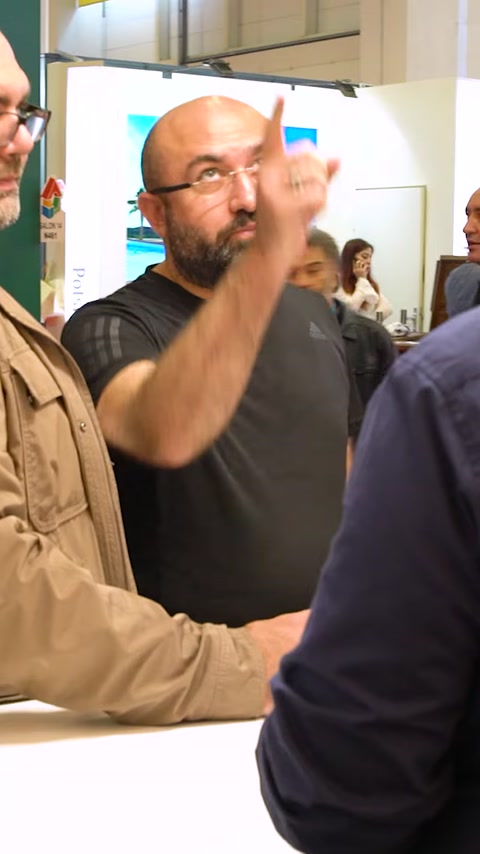 Uomo gesticola mentre parla all'ingresso dello stand espositivo