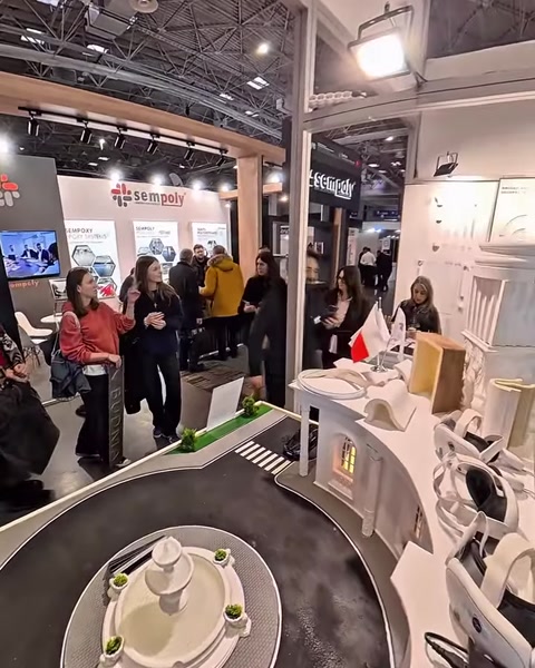 Visitatori riuniti attorno a uno stand con pannelli di profili per colonne e modanature