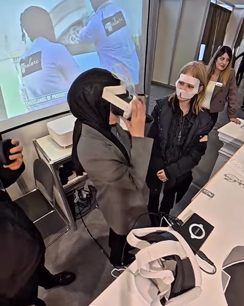 Una donna utilizza un visore per la realtà virtuale mentre colonne virtuali sono visibili su uno schermo vicino