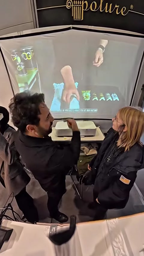 Man demonstrating VR headset while woman watches virtual hand on screen
