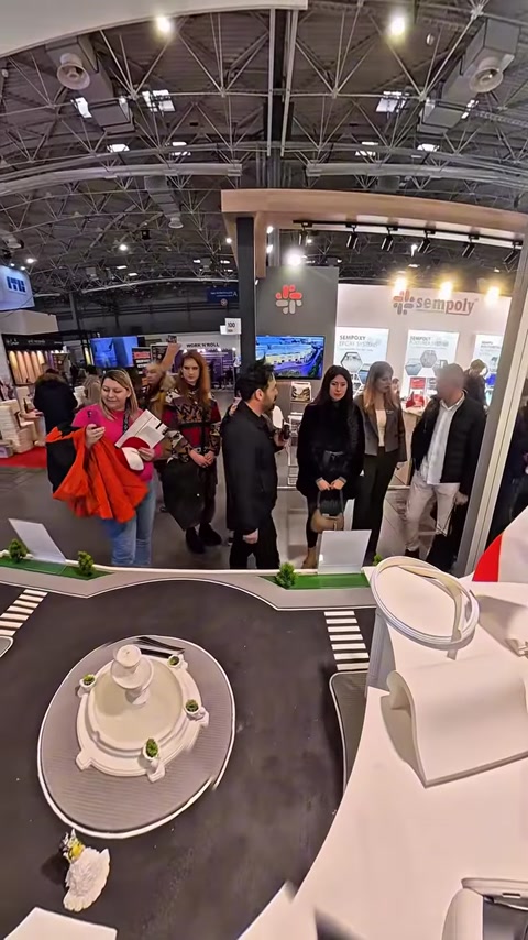 Crowd of visitors walking through exhibition hall near booth entrance