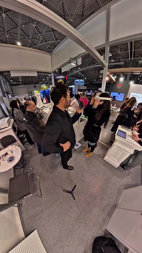 Man wearing VR headset gesturing while people watch nearby monitor