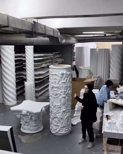 Twisted, fluted, and embossed column models are displayed in the production area.