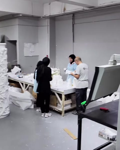 Workers inspect white decorative components before packaging.