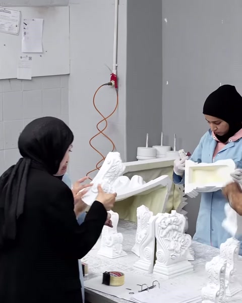 The surface of a decorative column capital is carefully examined by hand.