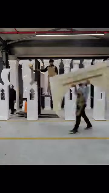 Çalışanlar, geniş kemerli dekoratif parçaları üretim alanında yerleştiriyor.