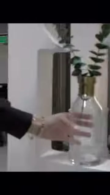 Altın başlıklı cam vazo, beyaz niş tabanına yerleştiriliyor.