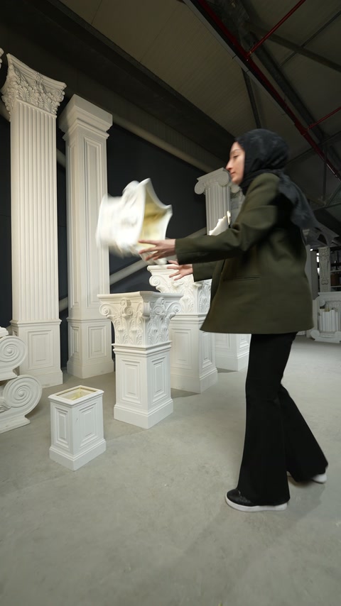 Worker carries an ornate capital among coordinated decorative column components