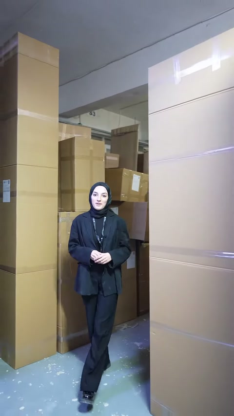 Düzenli istiflenen büyük koliler, sunucunun arkasında depo alanını dolduruyor.