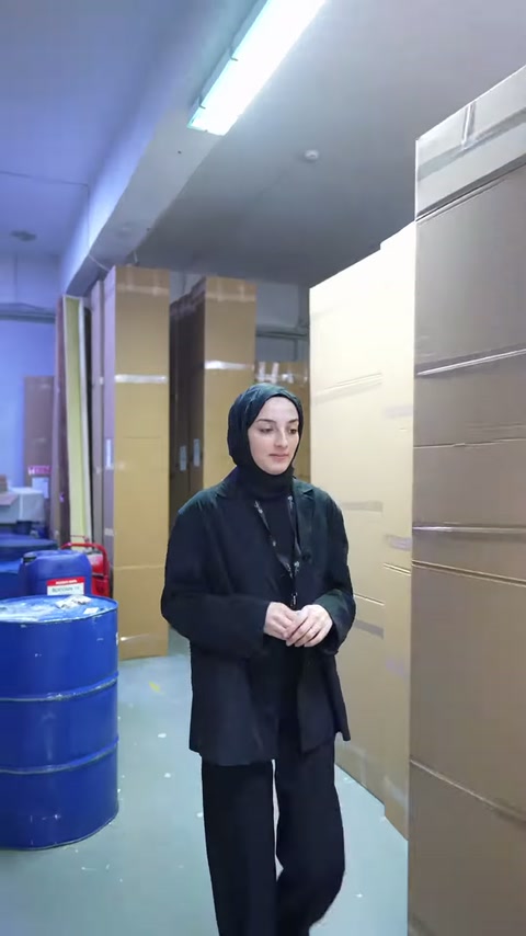 Sunucu, mavi varillerin yanındaki koli istifleri önünde duruyor.
