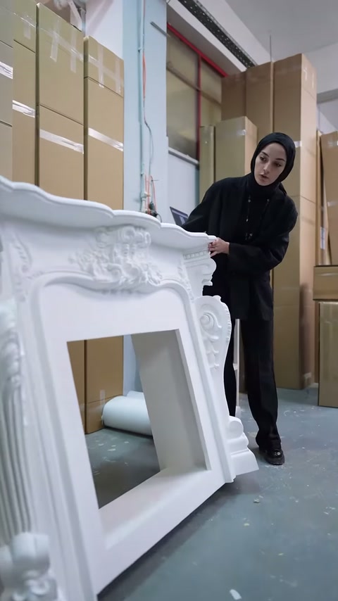Beyaz şömine çevresindeki kıvrımlı kabartmalar atölyede yakından gösteriliyor.