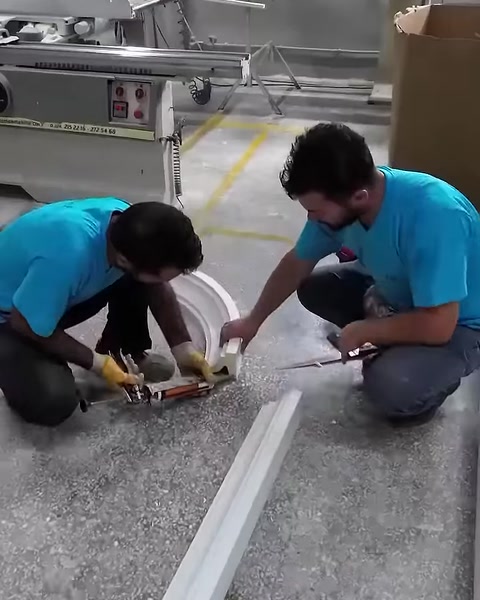 Gli operatori assemblano insieme gli elementi della cornice ad arco sul pavimento del laboratorio