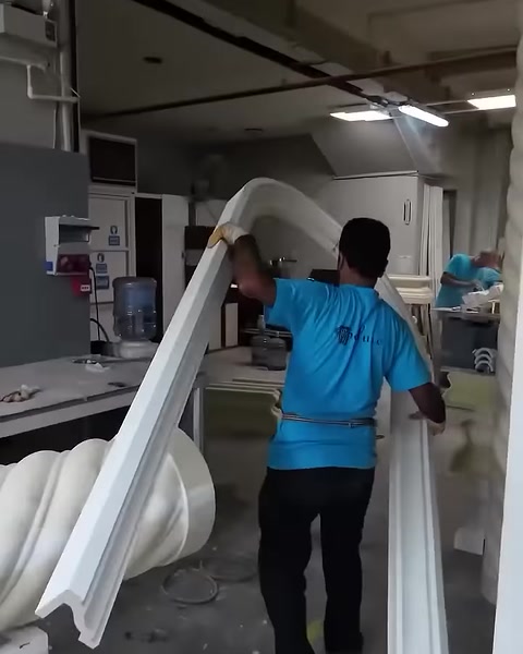 La cornice ad arco completata viene trasportata da due operatori in laboratorio