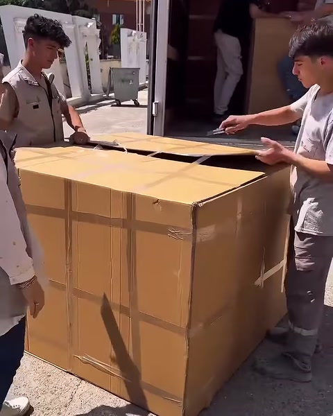 La squadra solleva le alette superiori della grande scatola dopo aver aperto le reggette.