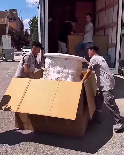 Due operatori estraggono con attenzione dalla scatola il capitello decorato.