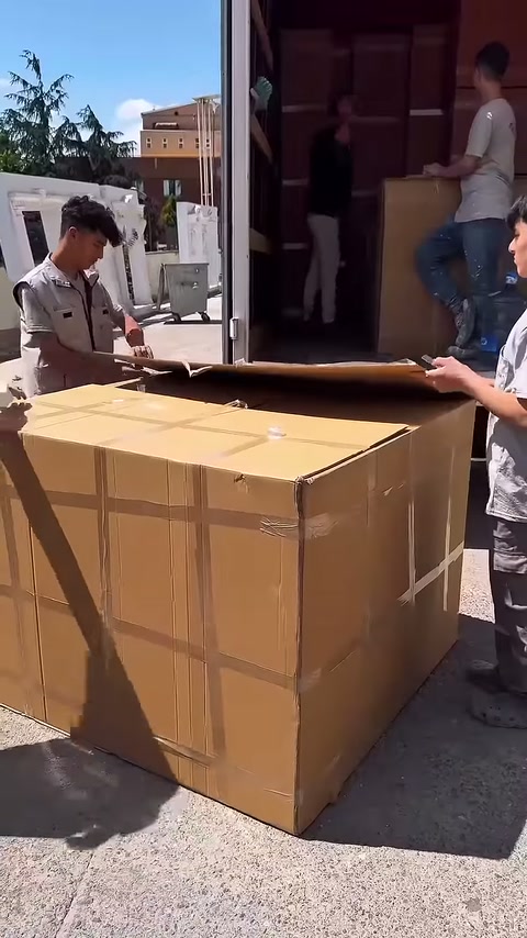 Un altro lavoratore tiene fermo lo scatolone mentre il coperchio viene sollevato
