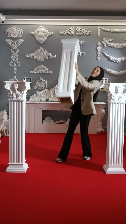 Presenter grasps a long-bodied white column segment with both hands.