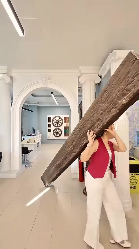 Woman carries lightweight beam past classical white pilasters and archway