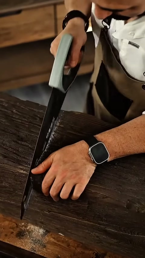 L'artigiano continua a segare la sezione marcata al banco di lavoro.