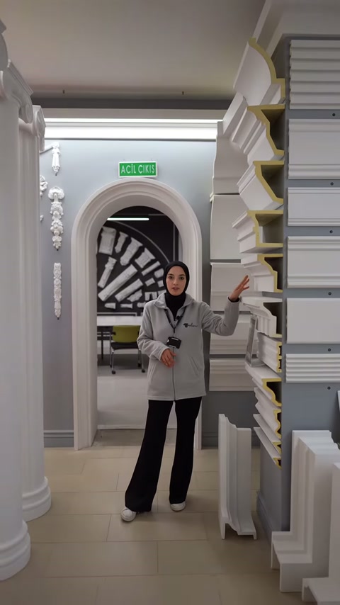 Il presentatore indica le opzioni di cornici marcapiano sulla parete dello showroom.