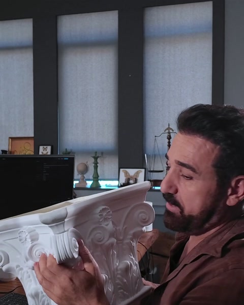 Presenter displays finished column capital sample on office desk