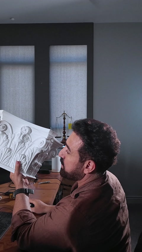 Primo piano di un grande campione di capitello di colonna in poliuretano tenuto dal designer