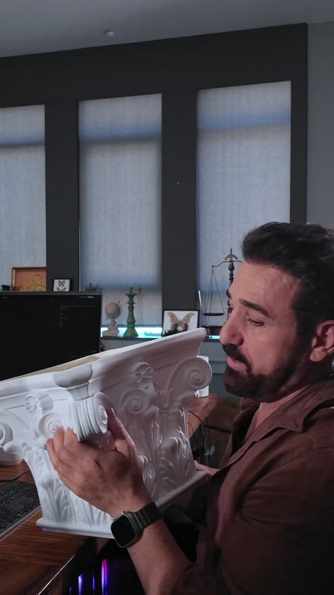 Il presentatore mostra il campione finito del capitello di colonna sulla scrivania dell'ufficio
