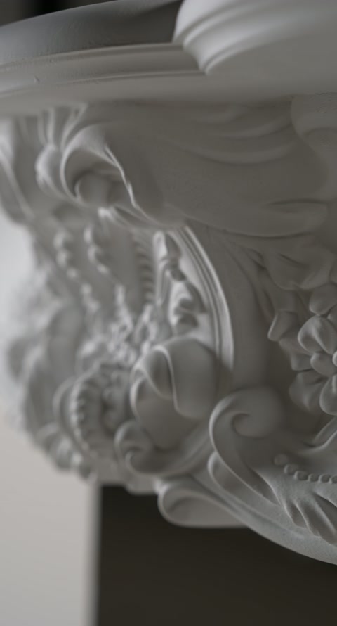 Close angled detail shows flowing foliage carved beneath the mantel edge.