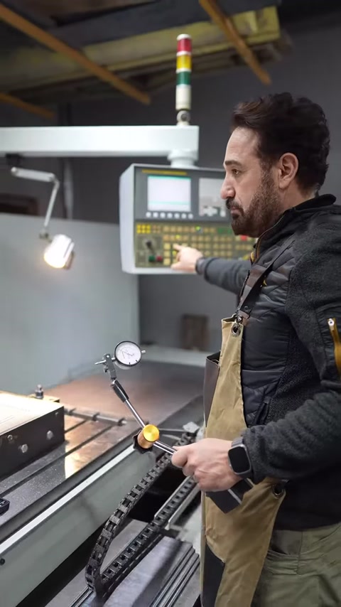 An operator manages production by adjusting the CNC machine from the control panel