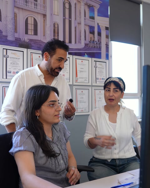 Il team di quattro persone tiene una consultazione di progetto davanti alla parete dei certificati
