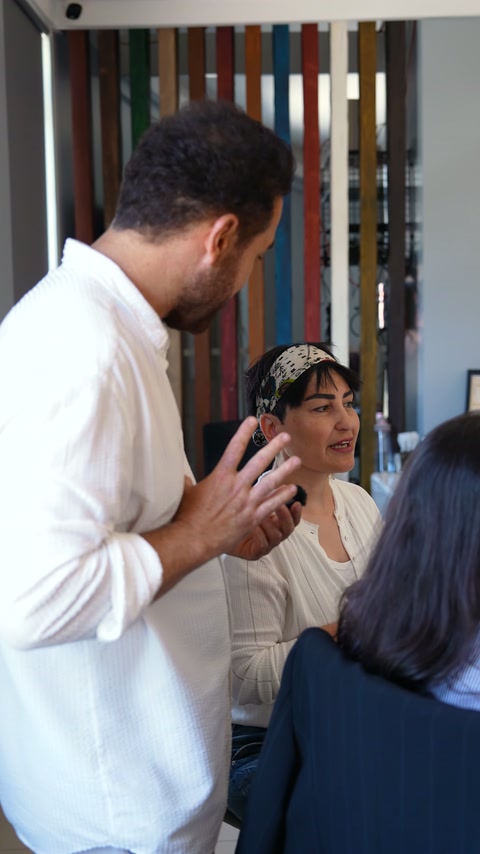 Selda discusses her design preferences verbally at a table.