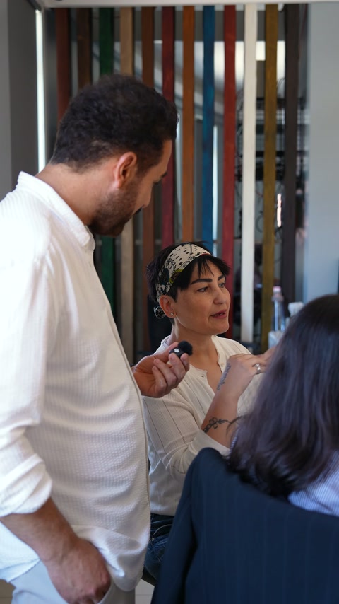 An expert listens to a seated designer's explanation about decorative application.