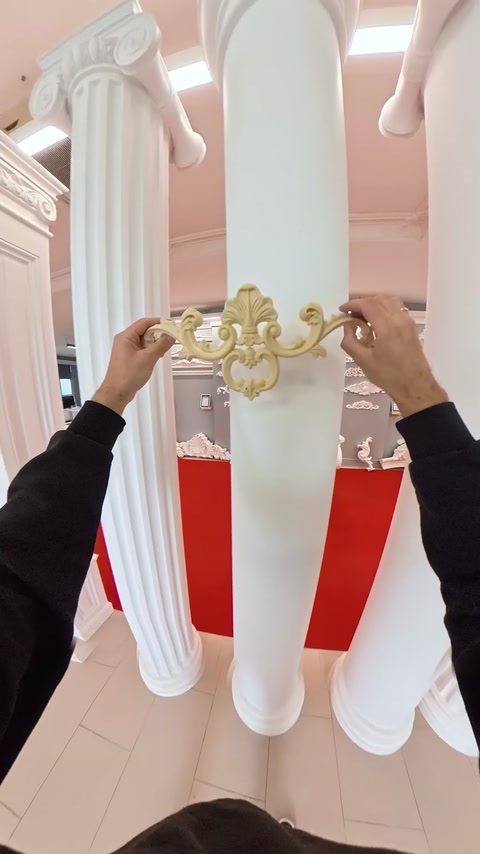 Symmetrical scroll applique piece displayed on a column surface