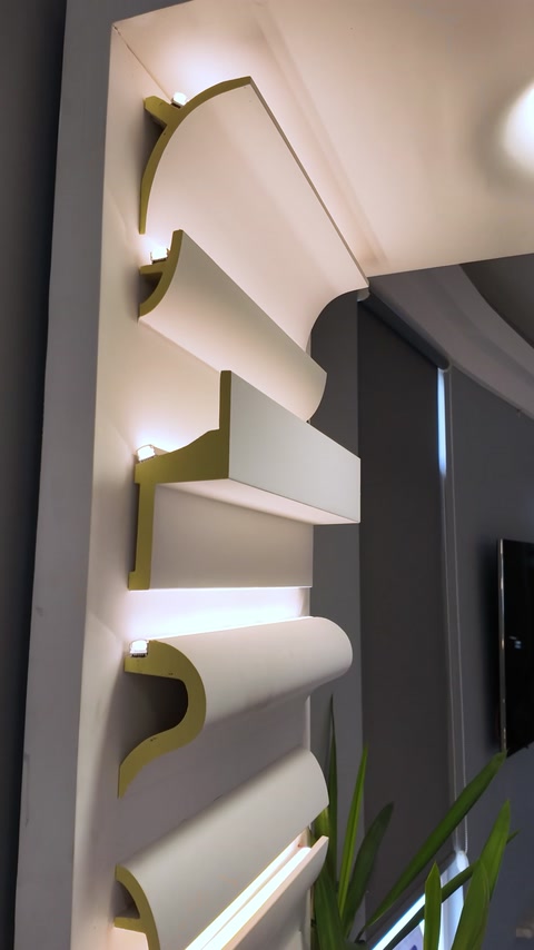 Curved polyurethane architectural profiles frame illuminated wall niches.