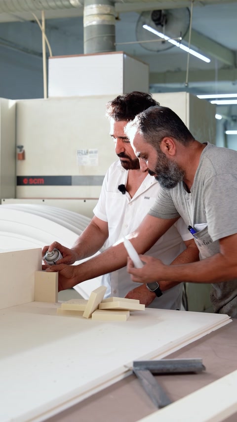 Craftsmen align a large curved arch profile on the workbench.