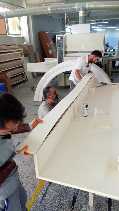 A craftsman shapes a long white decorative profile by hand.