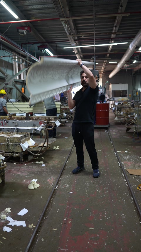 Factory worker handles a large curved molded architectural component.