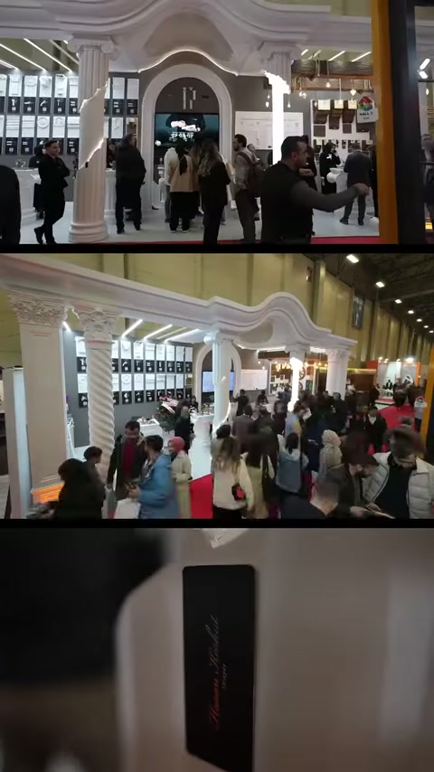 La facciata dello stand con archi e colonne scanalate è esposta in un'area fieristica affollata