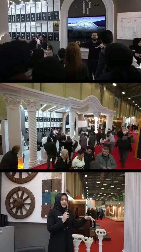 L'espositore parla accanto ai basamenti decorativi mentre la folla esamina lo stand