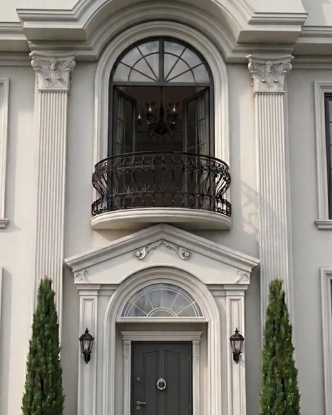 Villa entrance with tall pilasters, balcony railing and arched window