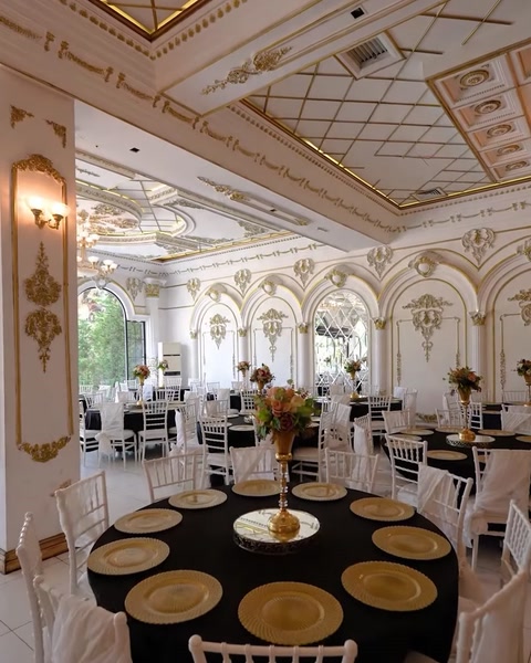 Banquet hall interior with round tables and gilded ceiling cornices