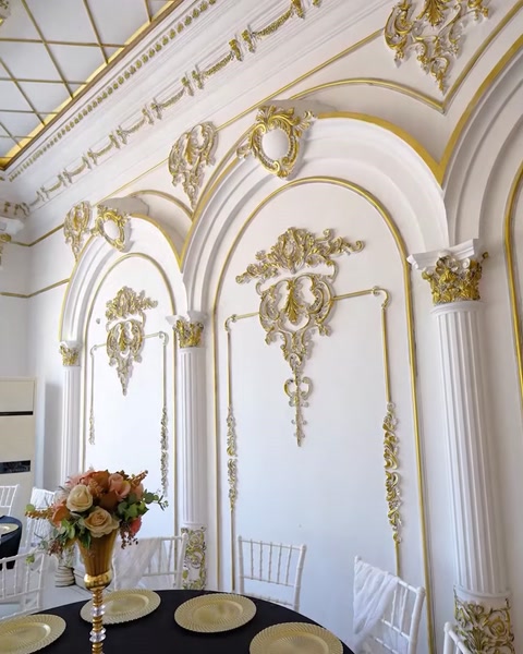 Wall panel with gold-trimmed decorative molding and floral vase