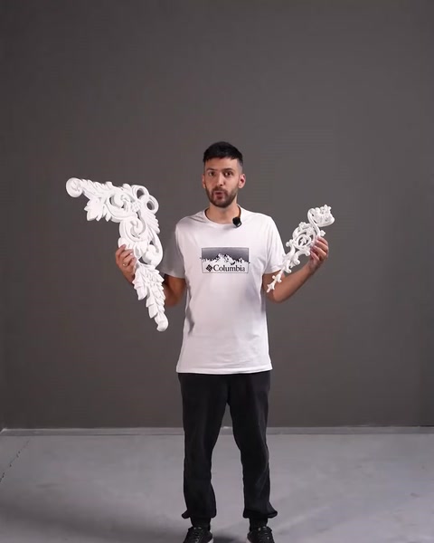 Presenter holding white decorative openwork architrave pieces in hands