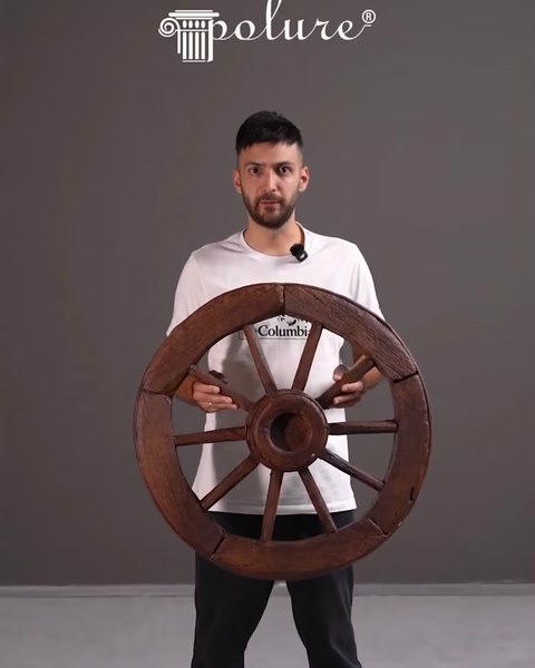 Presenter holding a large decorative wooden-style wheel